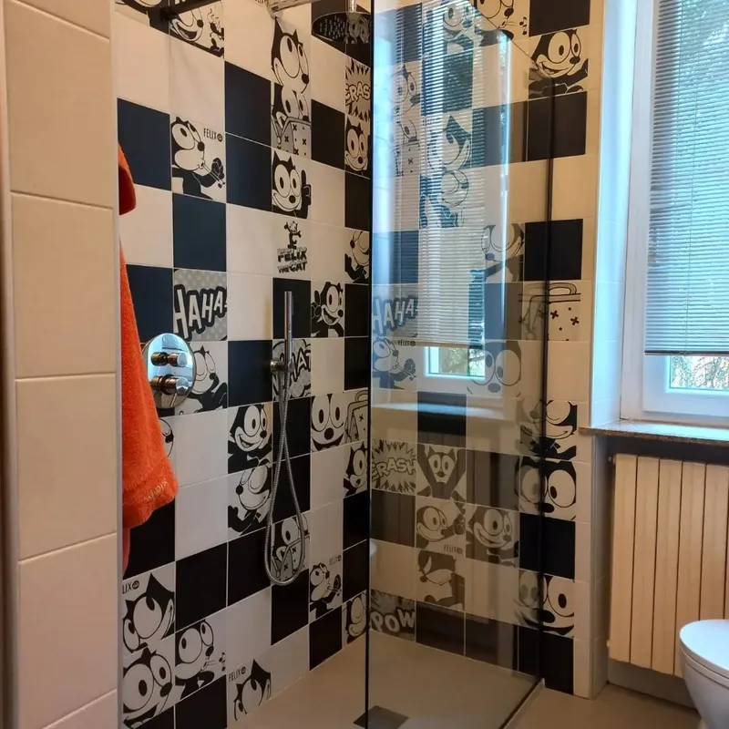 Doccia ristrutturata con piastrelle bianche e nere e mosaico raffigurante Felix the Cat.