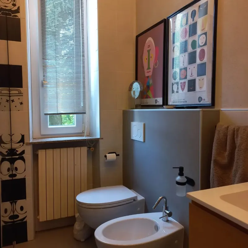 Zona sanitari del bagno ristrutturato con arredamento in stile pop e finiture bianco e nero.